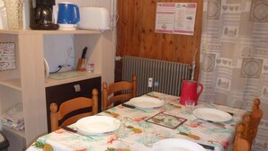 A dining area with a table set for four, featuring a tropical-themed tablecloth. - Studio for 4, Prime Ski Location, Balcony with Views, Wi-Fi, Pet-Friendly, Garage (Les Gets)