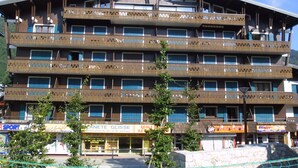 A multi-story hotel with balconies, a ski and surf shop, and a restaurant. - Studio for 4, Prime Ski Location, Balcony with Views, Wi-Fi, Pet-Friendly, Garage (Les Gets)
