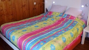 A bed with a colorful bedspread and two pillows. - Studio for 4, Prime Ski Location, Balcony with Views, Wi-Fi, Pet-Friendly, Garage (Les Gets)
