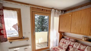 Una habitació acollidora amb un armari de fusta, un sofà amb funda estampada de cor, i una finestra amb vista a arbres.