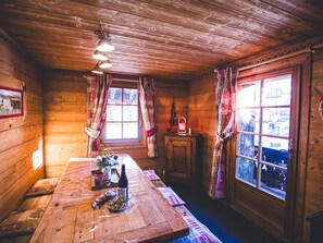 Cozy cabin interior with a dining table, wine, candle, and decorative centerpiece.
