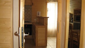 A wooden interior with a kitchen area, including a stove, sink, and cabinets.