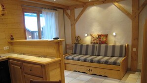 A cozy room with a wooden desk, a bench with cushions, and a window with curtains.