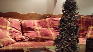A cozy living room with a wooden sofa, plaid cushions, a small Christmas tree, and a tray with a book. - Cozy family apartment in Les Gets with Wi-Fi, garage, 2 bedrooms (Les Gets)