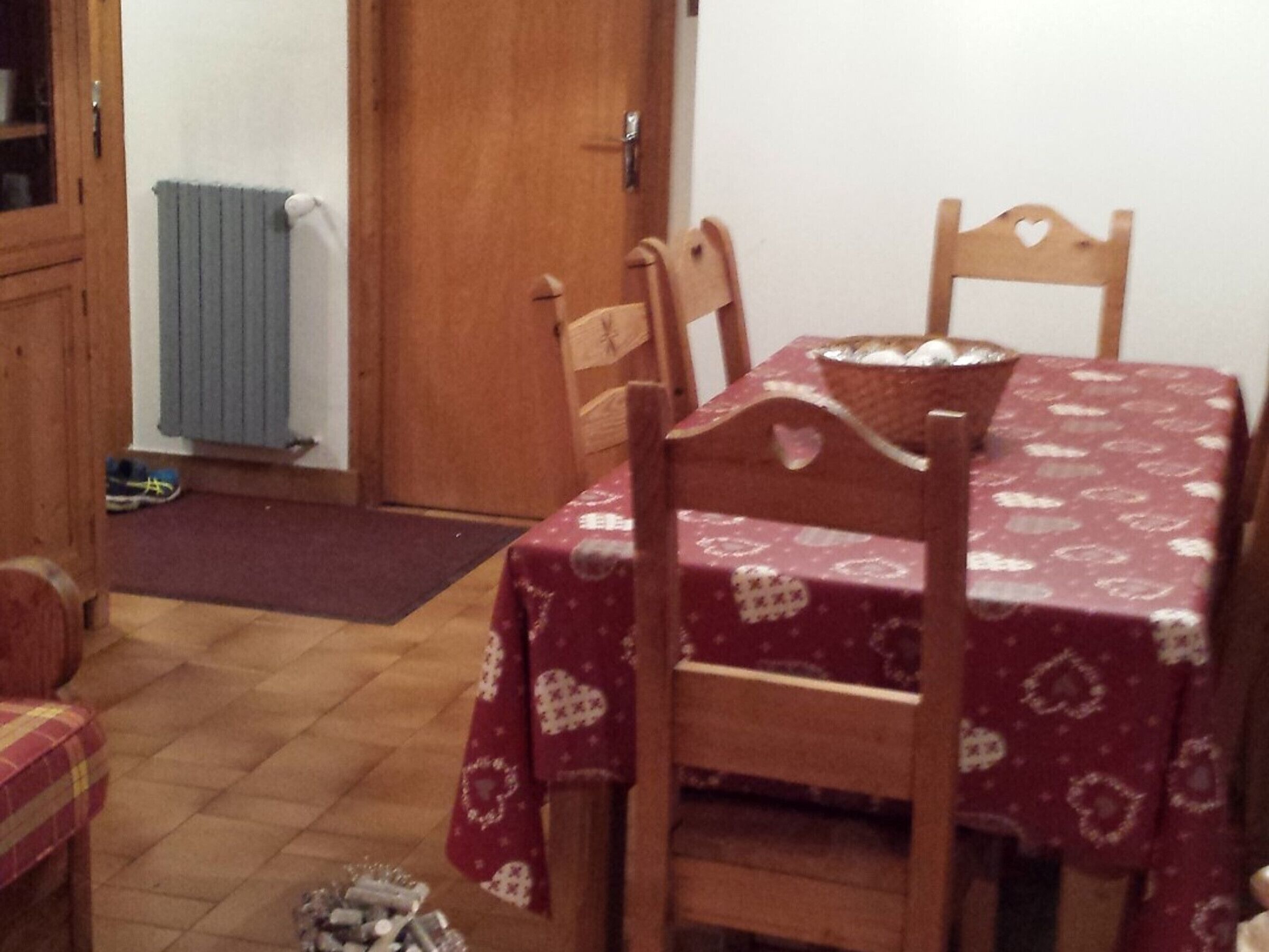 Un comedor con una mesa cubierta por un mantel estampado, sillas de madera y una cesta en la mesa.