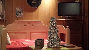 A cozy room with a wooden headboard bed, a small Christmas tree, a television on the wall, and a sign reading "Gozelle 2". - Cozy family apartment in Les Gets with Wi-Fi, garage, 2 bedrooms (Les Gets)