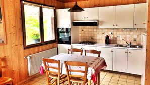 Un interior de madera con una mesa de comedor, sillas, una ventana, una estufa y armarios.