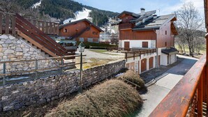 A traditional chalet-style building with a stone staircase leading up to a wooden deck. - Family Chalet for 8 in Courchevel Le Praz with Wifi (Courchevel)