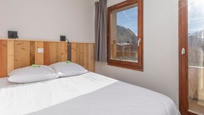A bedroom with a wooden headboard, a bed with white bedding, a window with a view of mountains, and a nightlight. - Charming renovated 2-room cabin for 6 with balcony in Avoriaz (Avoriaz)