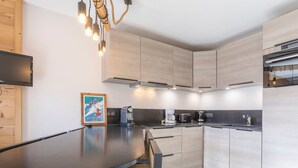 A modern kitchen with light wood cabinets, a black countertop, and stainless steel appliances. - Charming renovated 2-room cabin for 6 with balcony in Avoriaz (Avoriaz)