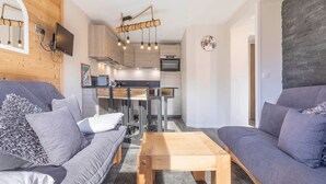 A modern living room with a sofa, a coffee table, and a kitchen area in the background. - Charming renovated 2-room cabin for 6 with balcony in Avoriaz (Avoriaz)