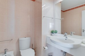 A modern bathroom with a toilet, sink, and mirror. - Apartment Falesia Paradise (Funchal)