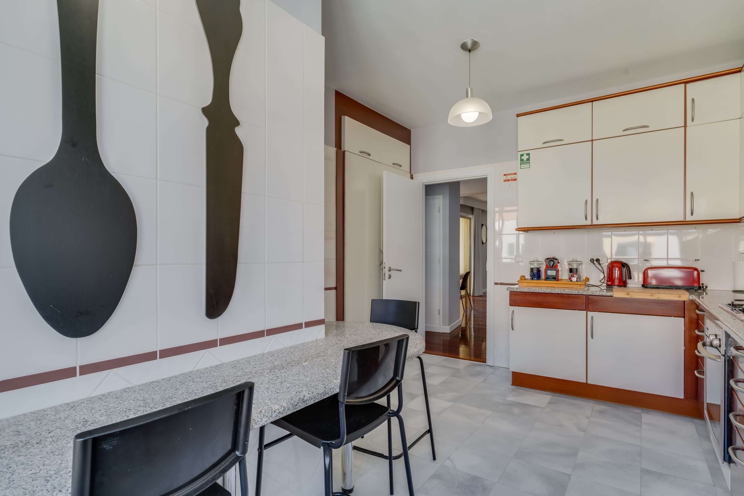 A modern kitchen with white cabinets, a granite countertop, and a dining area with two chairs.