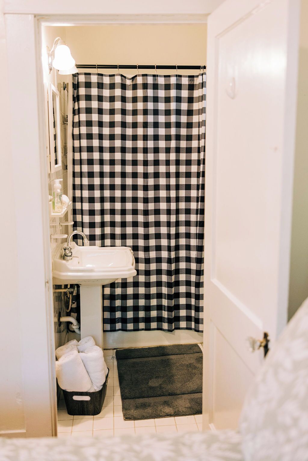A bathroom with a checkered shower curtain, a sink, and a small rug.