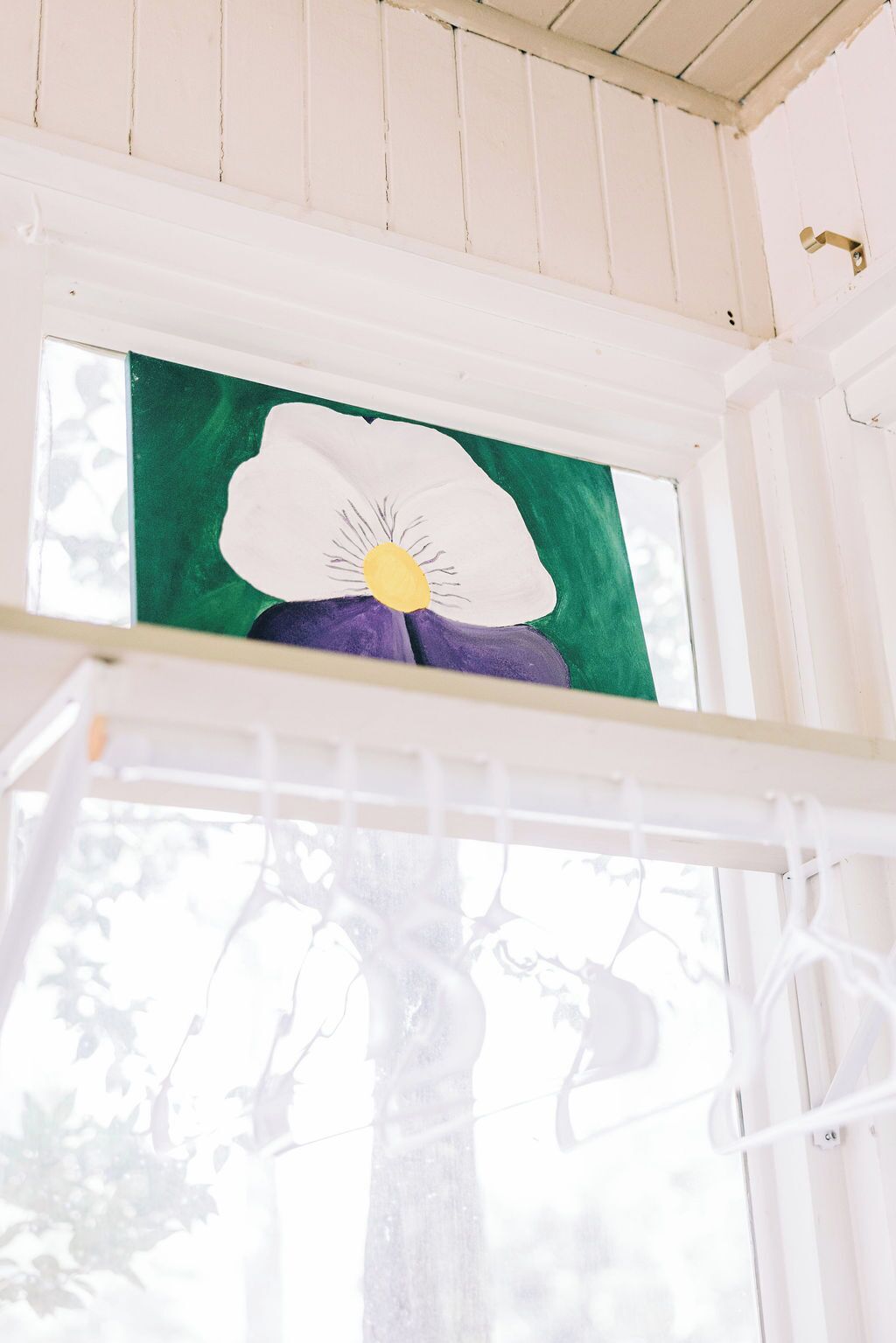 Ein Fenster mit einer grüngrauen Blumenmalerei.