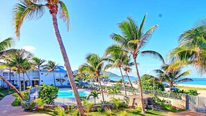 A resort with a swimming pool, palm trees, and a beach view.