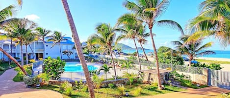 Un resort con piscina, palmeras y vista al mar.