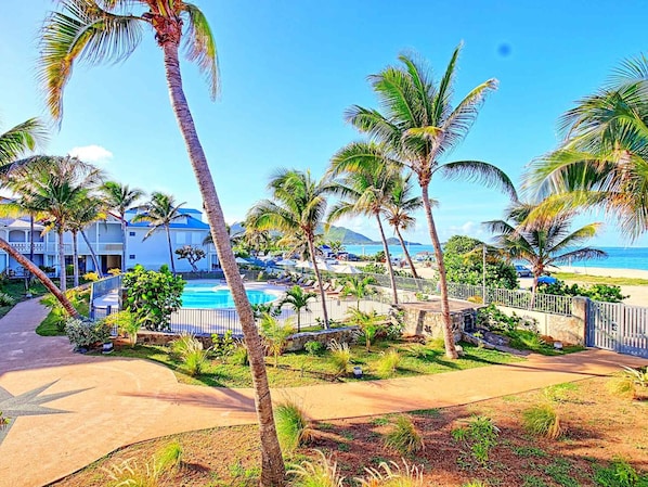 A resort with a swimming pool, palm trees, and a beach view.
