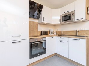 A modern kitchen with white cabinets, a microwave, a coffee maker, and a sink.