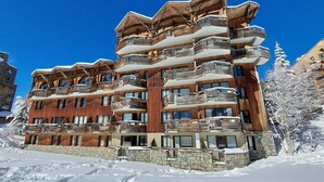Ein mehrstöckiges Hotel mit hölzernen Balkonen und einer Steinfassade, umgeben von Schnee.