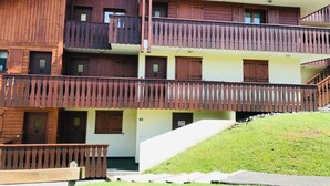 A multi-story wooden building with balconies, a staircase, and a grassy area in front. - Cozy apartment in Morillon, 6 people, near Criou (Morillon Village)