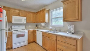 A kitchen with wooden cabinets, a microwave, stove, dishwasher, and a coffee maker. - Modern 3/2.5 near everything! Smryna- Off I-24! (Smyrna)