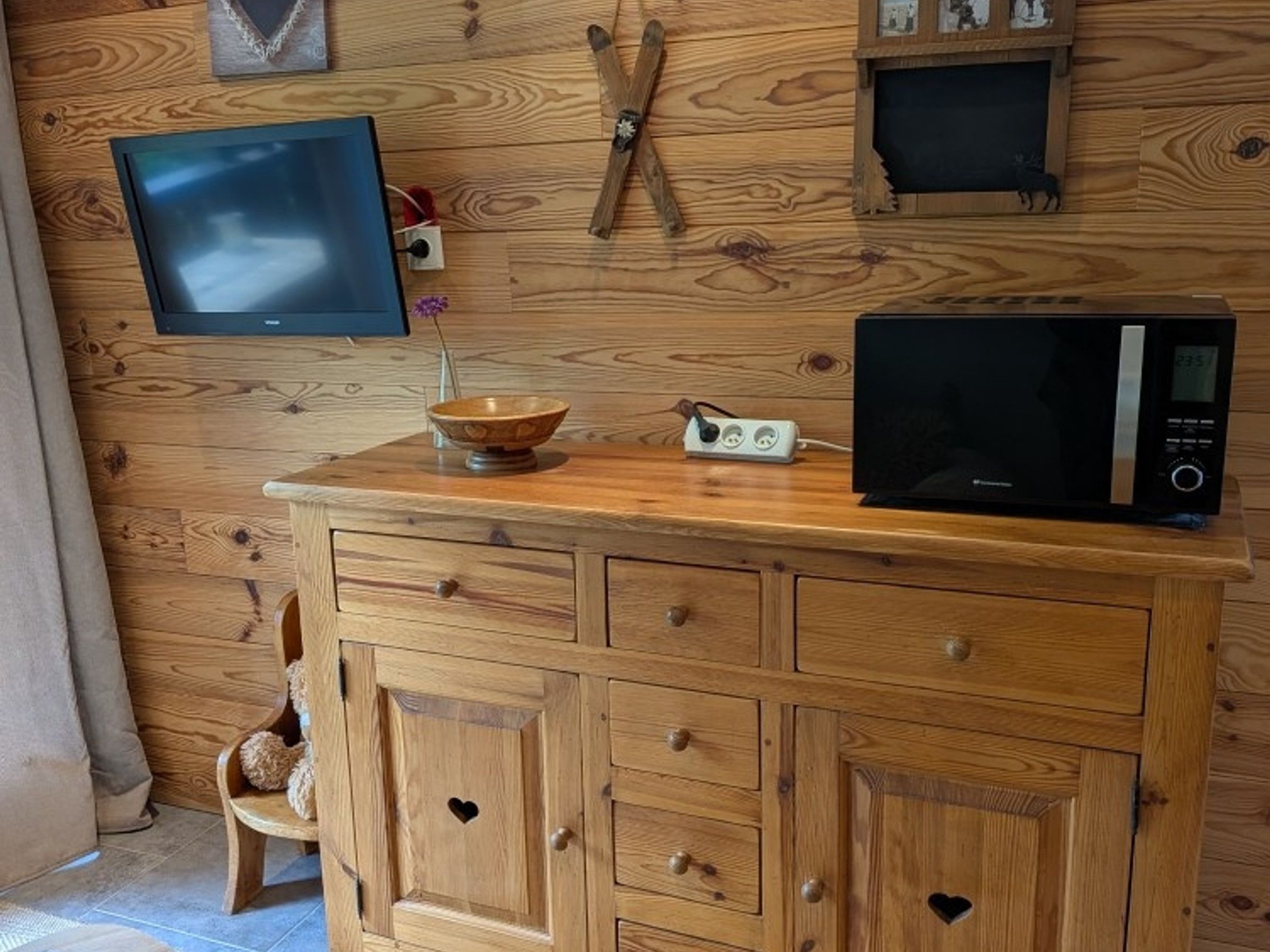 Un meuble en bois avec des tiroirs et un four à micro-ondes posé sur le dessus.