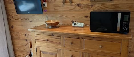 Un mobiletto in legno con cassetti e un forno a microonde sopra.