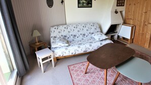 A cozy room with a patterned sofa, a small table, a lamp, and a fireplace. - Renovated studio for 4 with fireplace in Avoriaz (Avoriaz)