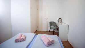 A room with two beds, a desk, and a chair.