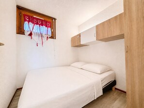Ein Schlafzimmer mit einem Bett, einem Holzschrank und einem Fenster mit Vorhängen.