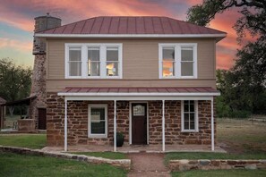 A two-story house with a stone foundation and a metal roof. - Mildred Haus and Guesthaus (Mason)