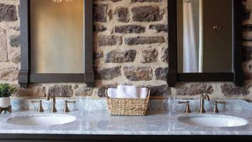 A bathroom with two sinks, a stone wall, and a mirror.