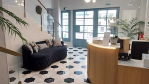Zona de recepción con un sofá negro, un mostrador de madera y un suelo con estampado geométrico.