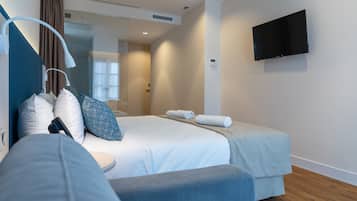 Una habitación de hotel moderna con una cama, un televisor montado en la pared y una ventana con cortinas.