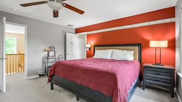A bedroom with a bed, a nightstand, a lamp, a ceiling fan, and a door leading to a balcony.