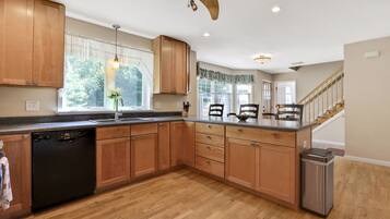 A kitchen with wooden cabinets, a dishwasher, a sink, and a trash can.