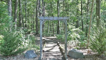 Ein hölzerner Kletterbogen mit einem Steinweg, der durch einen Wald führt.