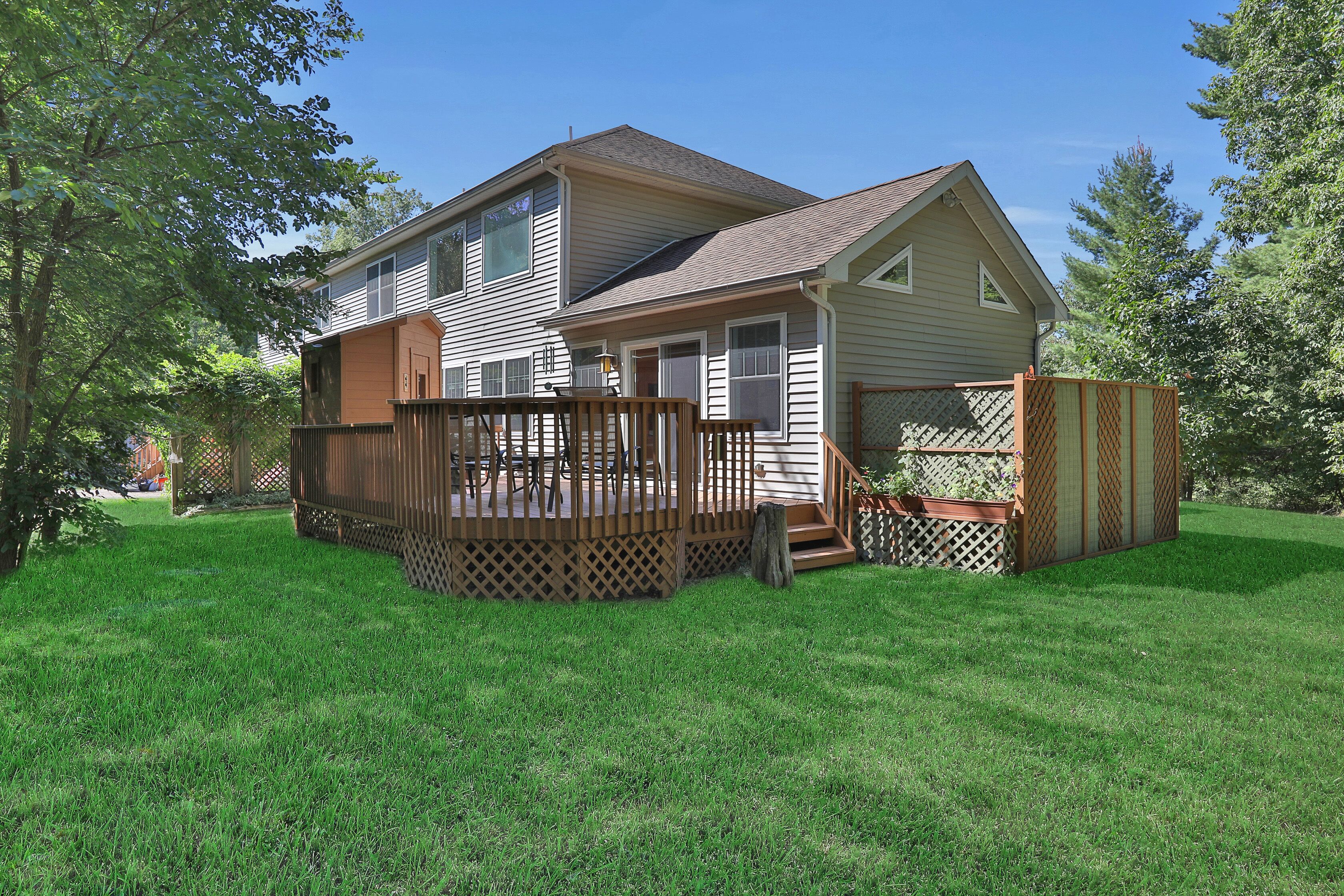 A two-story house with a deck and a fenced yard.