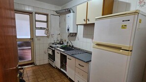 A compact kitchen with white cabinets, a refrigerator, a stove, and a sink. - Exquisito 3 ambientes Congreso (Buenos Aires)