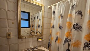 A bathroom with a white tiled wall, a pedestal sink, a mirror with a gold frame, and a shower curtain with a palm leaf pattern. - Exquisito 3 ambientes Congreso (Buenos Aires)