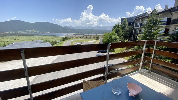 Ein Balkon mit Blick auf einen See, Berge und eine Straße mit Autos.