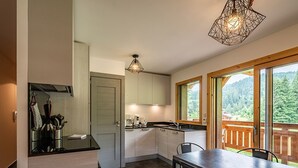 Een moderne keuken met een eetgedeelte, grote ramen en uitzicht op de omgeving.