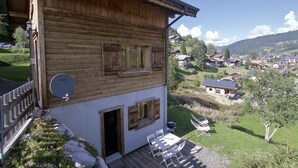 Un chalet en bois doté d’un balcon, d’une antenne parabolique et offrant une vue sur un village.