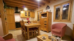Un salon chaleureux avec une table à manger en bois, un fauteuil rouge et une table basse agrémentée de services à thé.
