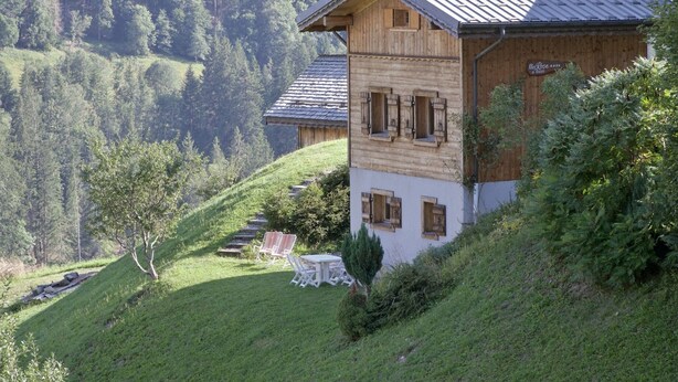 Un chalet en bois avec un toit en pente, un petit balcon et une enseigne indiquant la présence d’un restaurant.