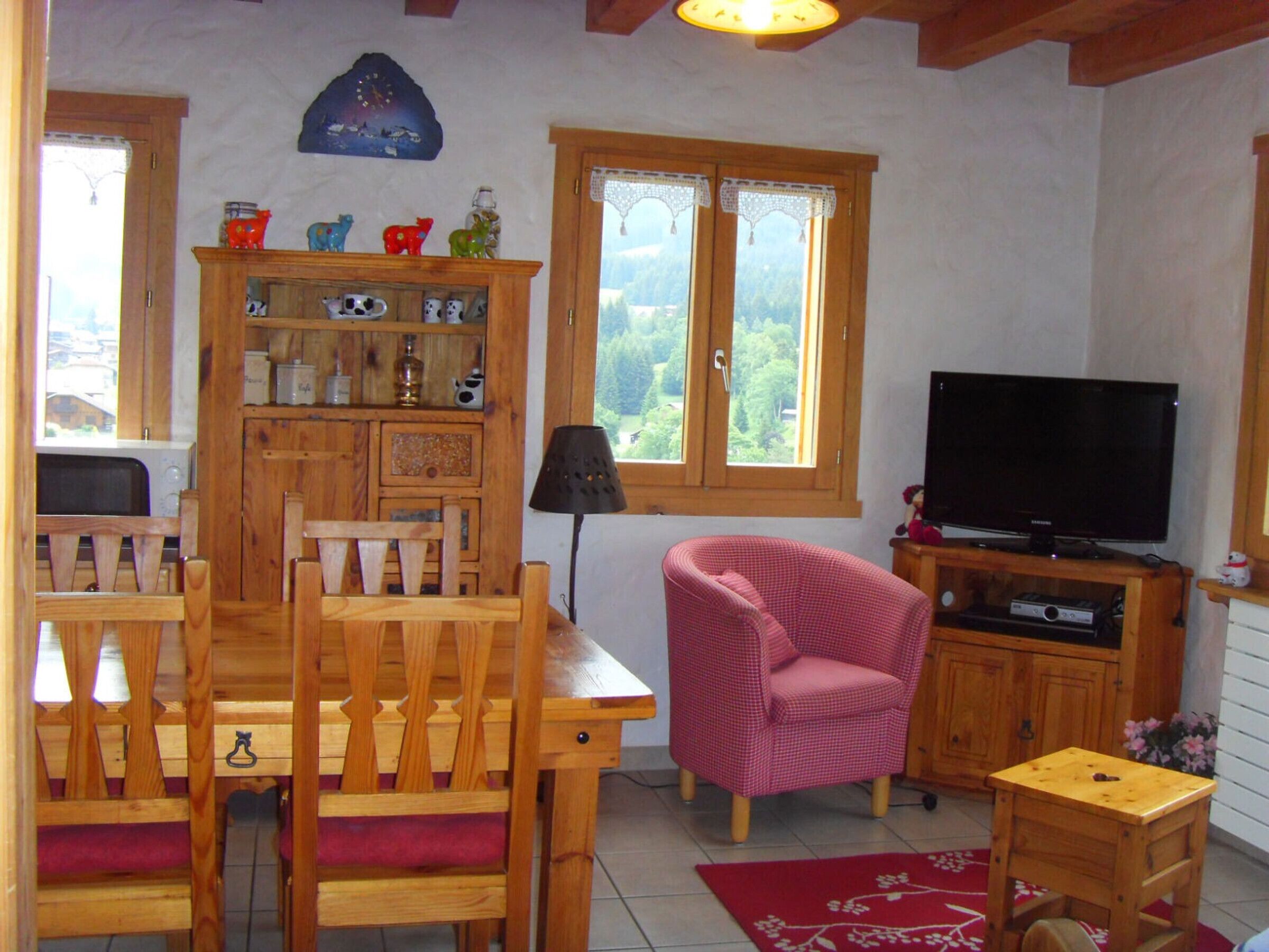 A cozy living room with a wooden dining table, chairs, a television, and a bookshelf.
