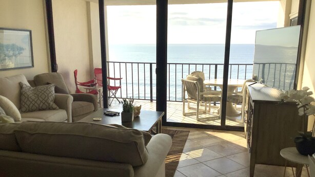 A living room with a sofa, a coffee table, and a TV. There is a balcony with a view of the ocean. - Oceanfront Beautiful Views 2 Bd and 2 Baths Family-Friendly Lovely Furnishings (Myrtle Beach)