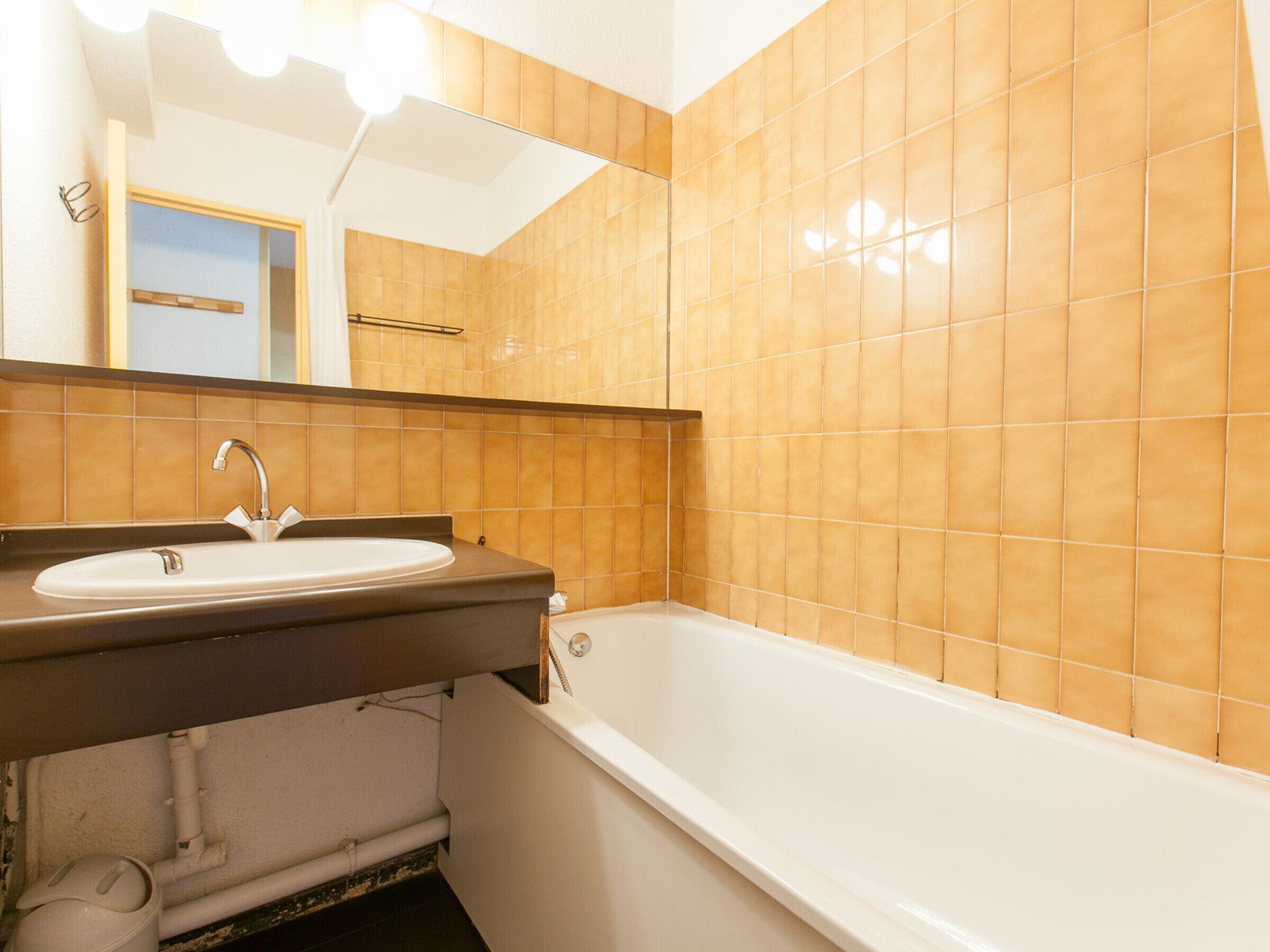 A bathroom with a sink, mirror, and bathtub.