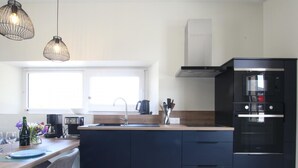 Una cocina moderna con una isla central, horno empotrado y cafetera.